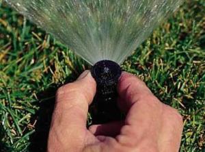 the Grand Prairie Sprinkler Repair team adjusts pop up heads by hand