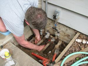 a sprinkler repair tech checks the connections for a sprinker system